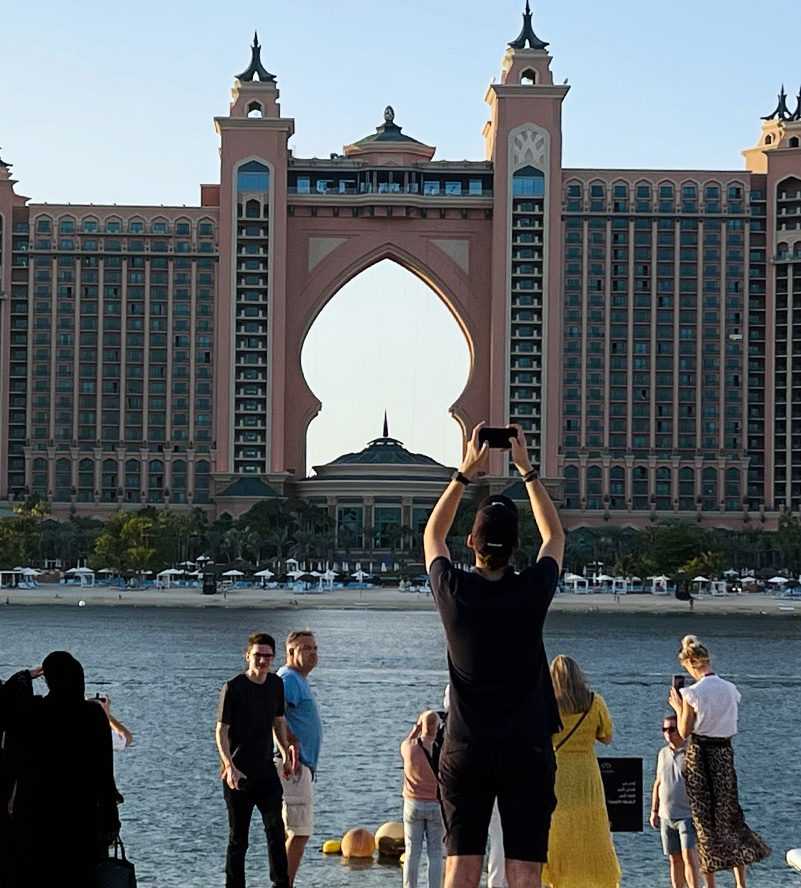A couple enjoying the beach in front of a atlantis hotel, with the serene ocean as their backdrop-