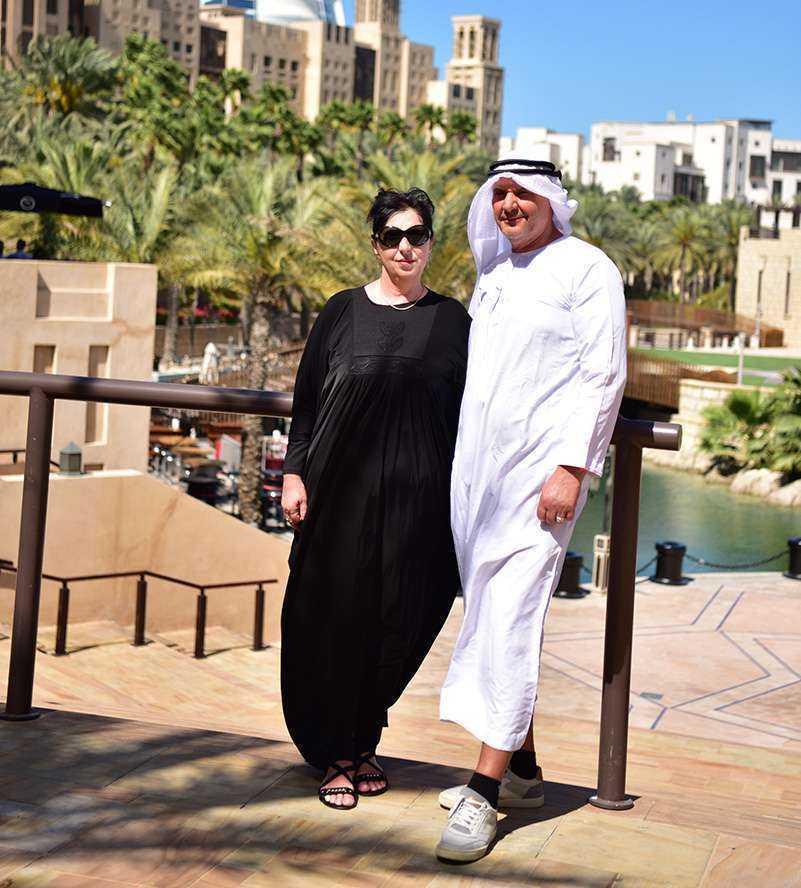 A couple in black attire standing on a balcony, overlooking a scenic view dubai-burj-khalifa