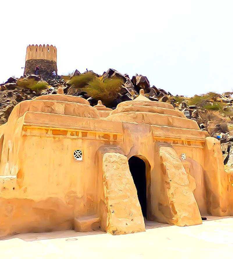 A desert building entrance, surrounded by vast sand dunes, stands as a solitary structure in the arid landscape Al Bidya Mosque