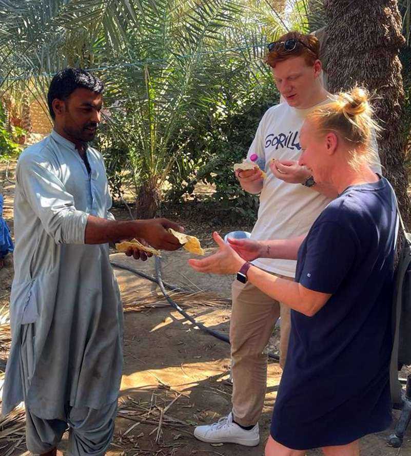 A man kindly offers food to a woman and another man oase Al Ain