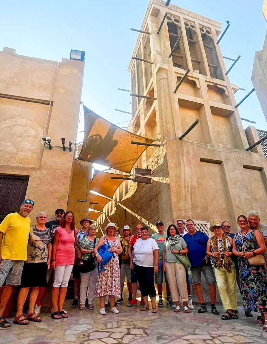 Das alte Dubai mit Dubai Frame - Al Fahidi Historical Neighbourhood-A diverse group of individuals standing in front of a majestic building