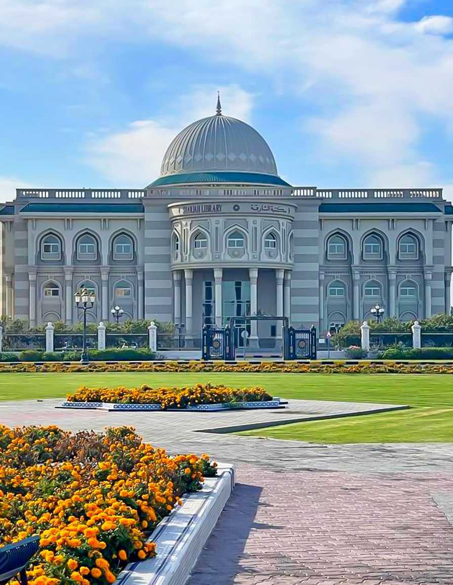 „Die Öffentliche Bibliothek von Sharjah. Dieses bedeutende Kulturzentrum befindet sich am Kulturplatz (auch bekannt als Buch- oder Quran-Kreisverkehr) im Emirat Sharjah.“