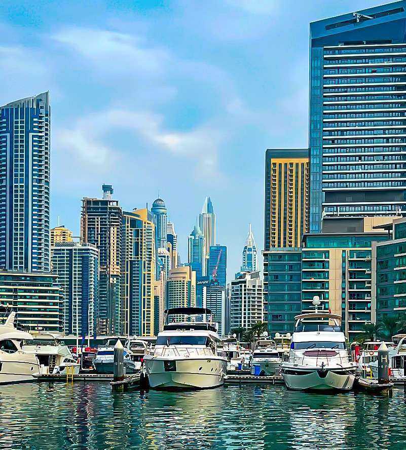 Boats docked near tall buildings in the water Dubai