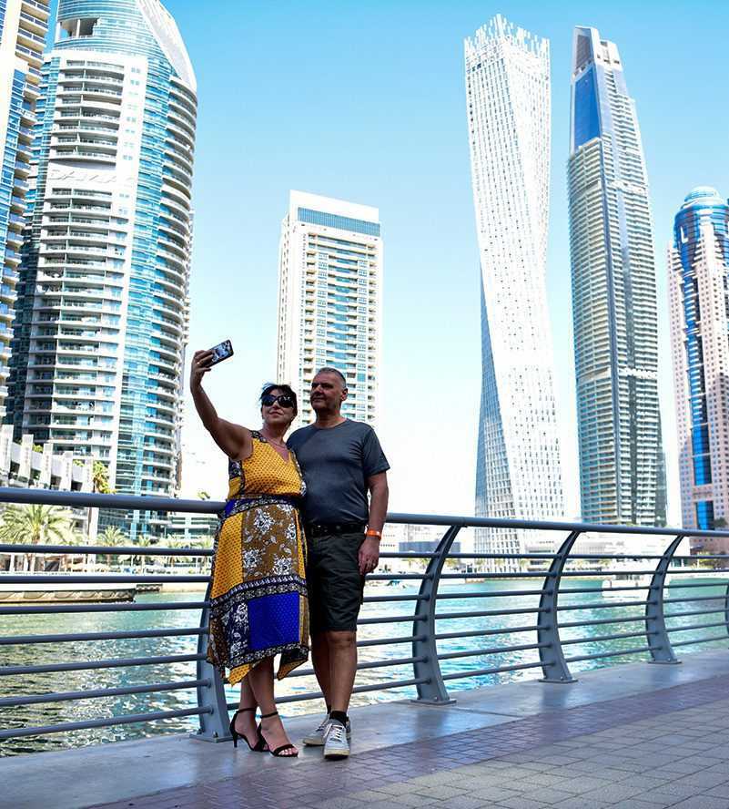 Dubai city tour A couple capturing a moment together as they take a selfie in front of a bustling cityscape