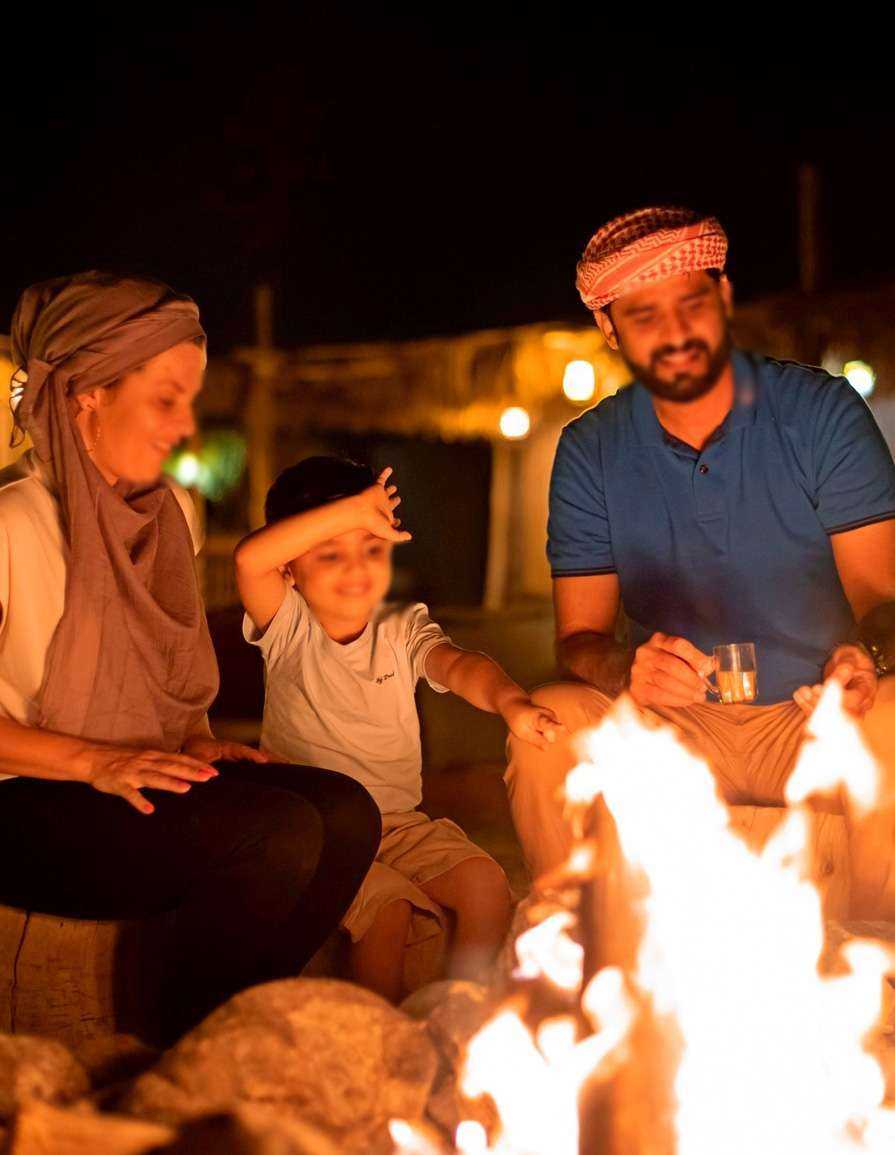 Family gathered around campfire at night Dubai