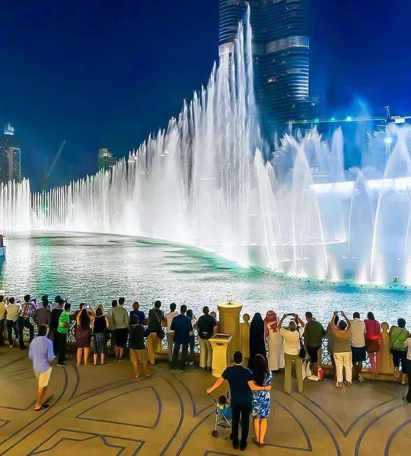 Nighttime fountain viewing with building backdrop and spectators Dubai