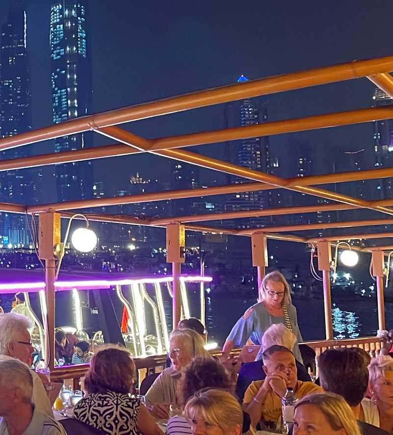 People dining on a boat with a city skyline in the background. Enjoying a meal while admiring the urban landscape-Cruise Dubai