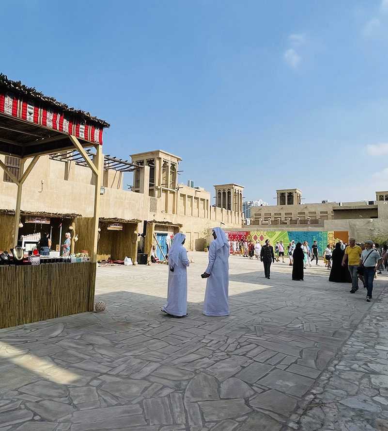 People walking in an open courtyard with a few shops-Dubai market