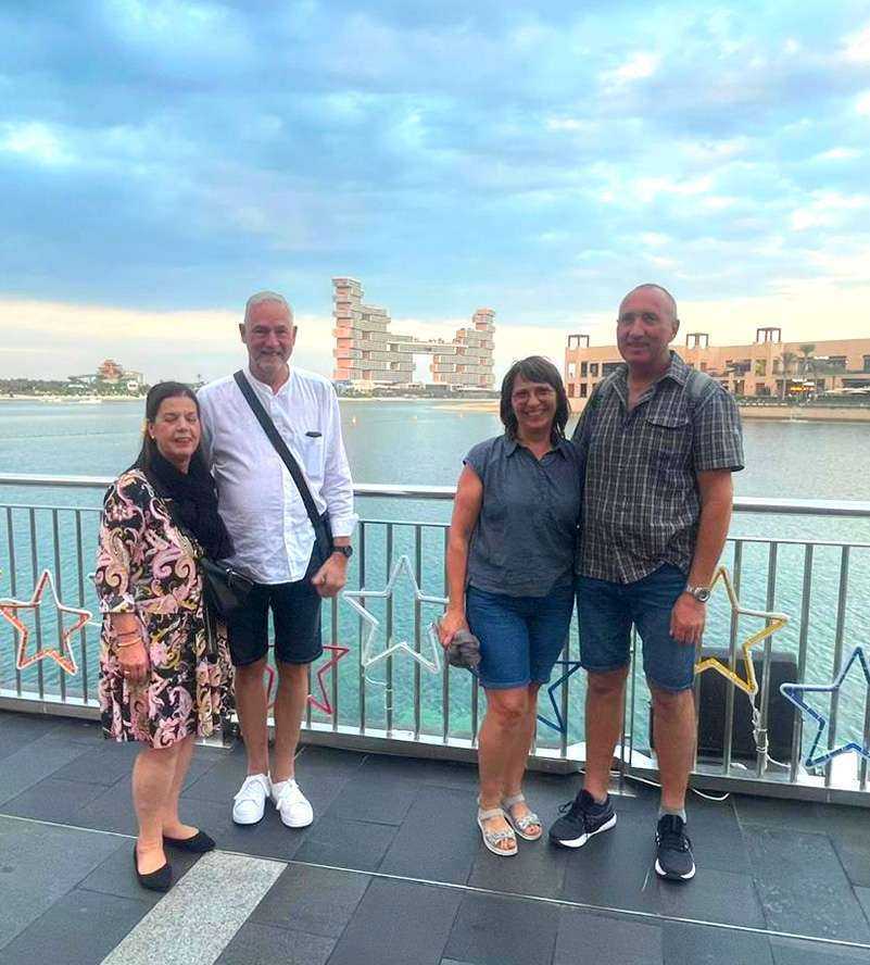Three individuals standing on a bridge overlooking the water Burj Al Arab hotel