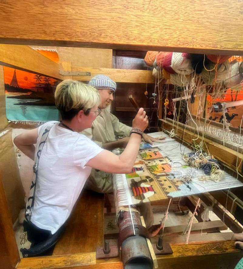 Two individuals operating a weaving machine, creating intricate patterns with precision and skill