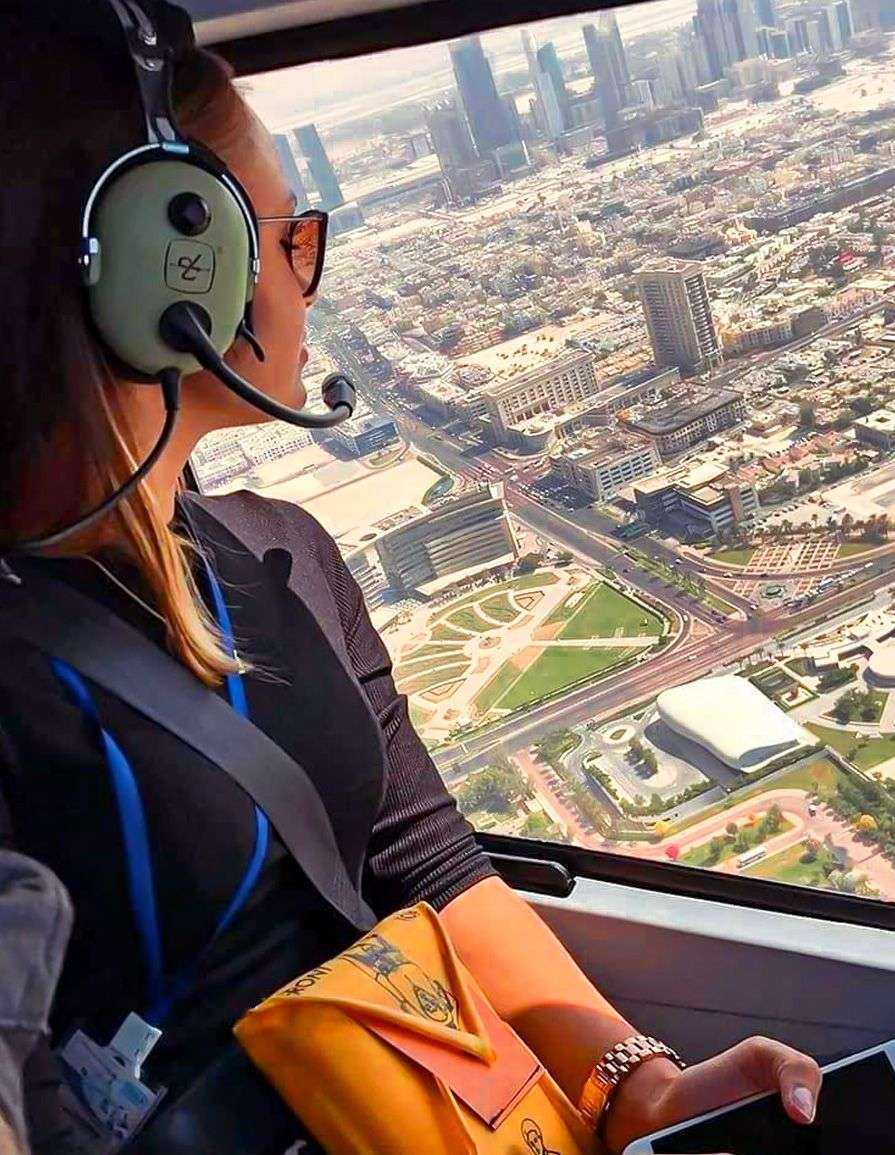 person in a headset looking out a window helicopter flying over Dubai city
