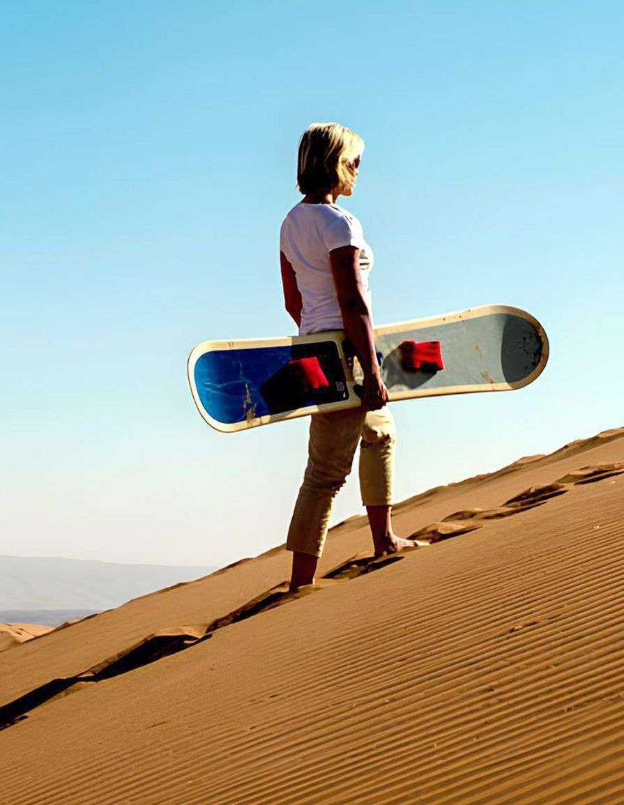 a person holding a snowboard on a sand dune dubai