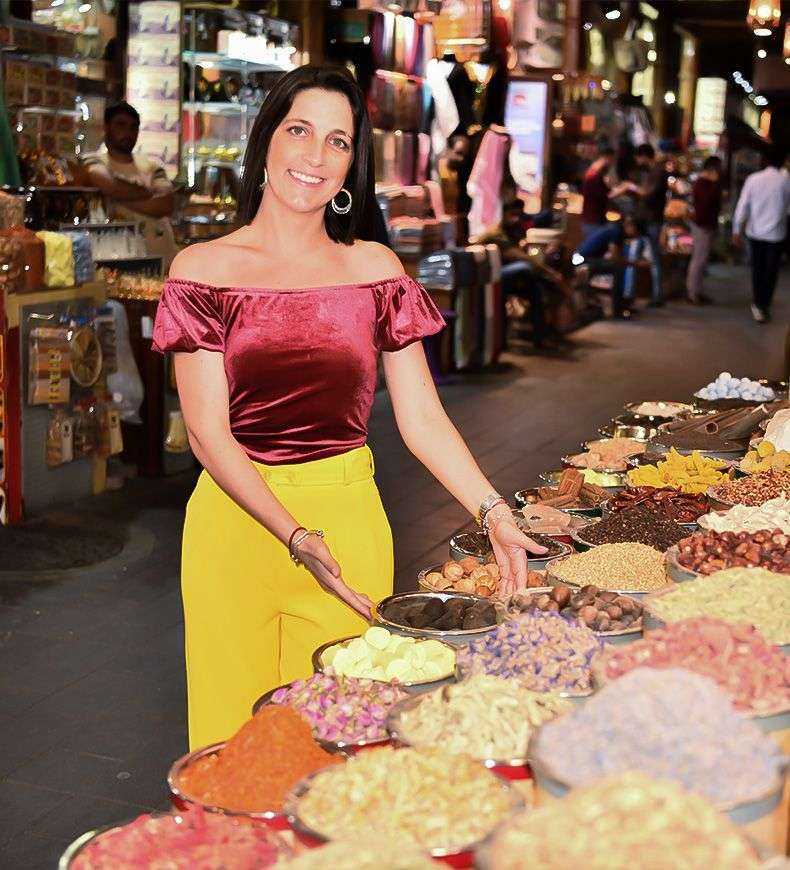 a person standing in front of a display of food Duabi at night