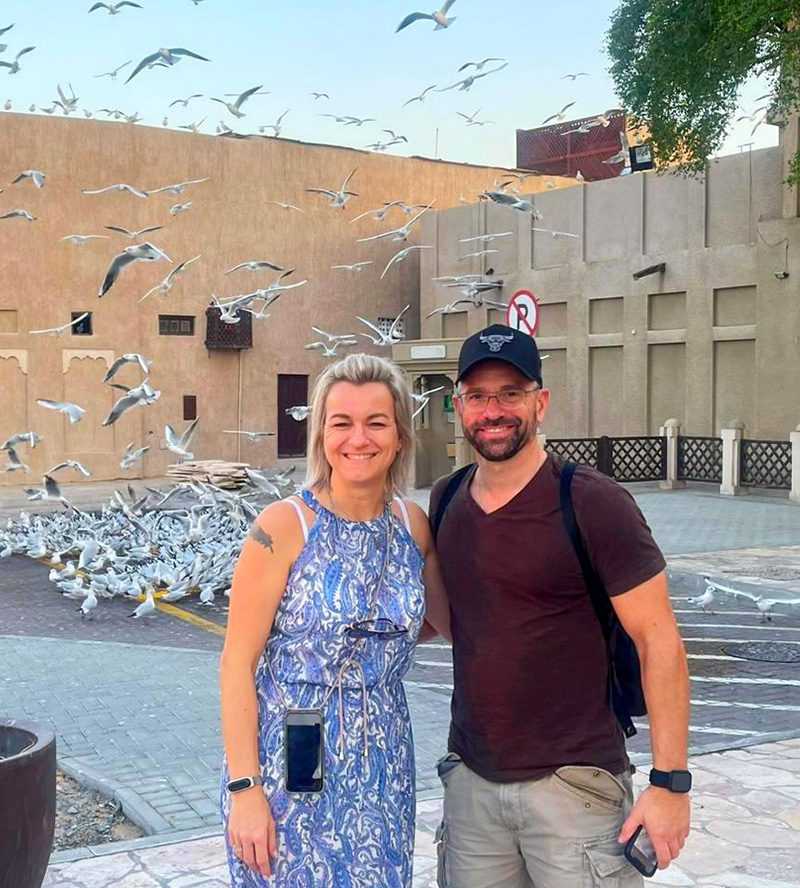 couple smiling for a photo with a flock of birds-Dubai Sightseeing Tour
