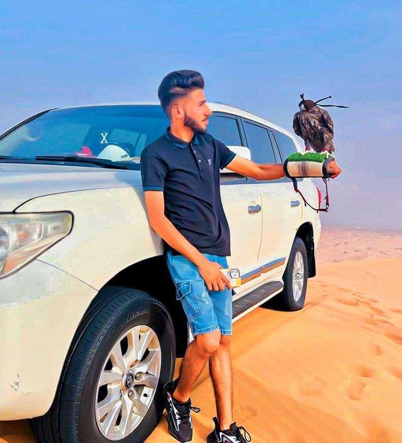 person holding a bird on his arm next to a car Dubai safari