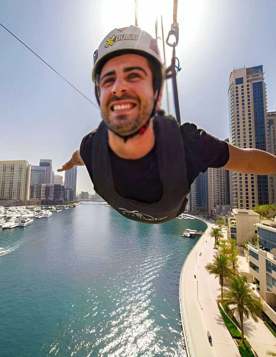 person in a helmet flying through a rope over Dubai Marina