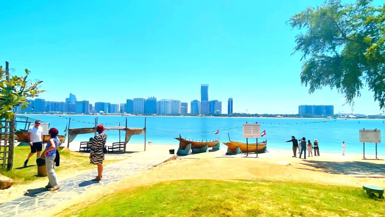 Der Strand im Heritage Village mit traditionellen Fischerbooten und Blick auf die Skyline von Abu Dhabi.