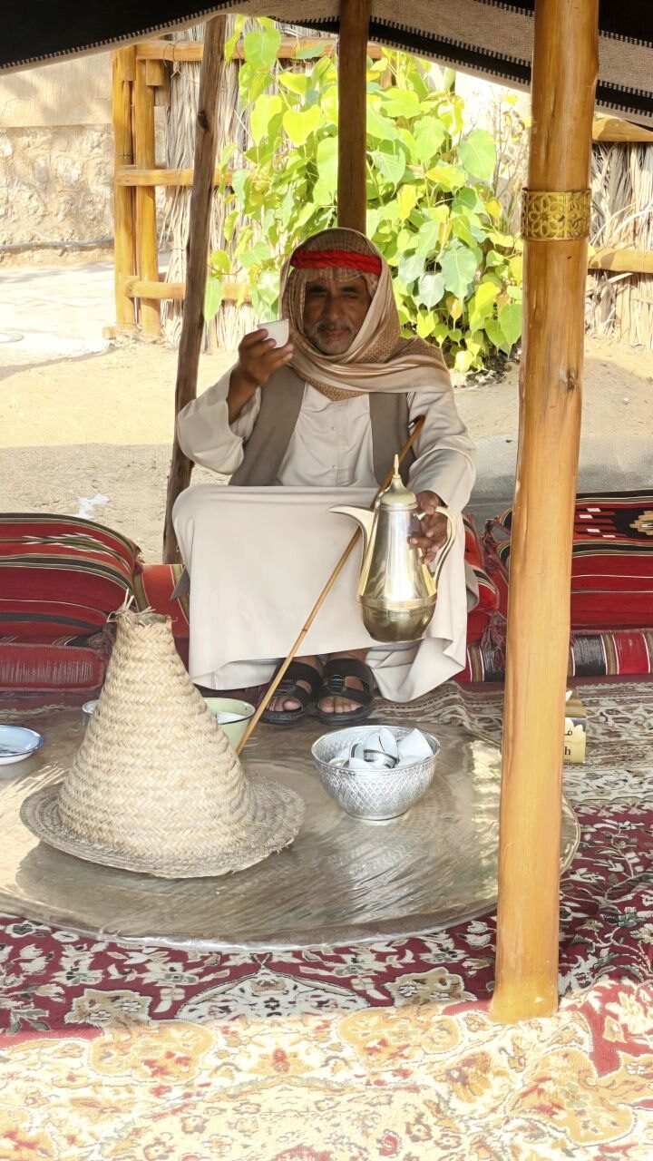 Kaffeekanne und Tasse in den Händen eines Mannes im alten Dubai – symbolisieren das wichtigste Kulturerbe der VAE, beliebtes Fotomotiv und kulturelles Erlebnis für Touristen.
