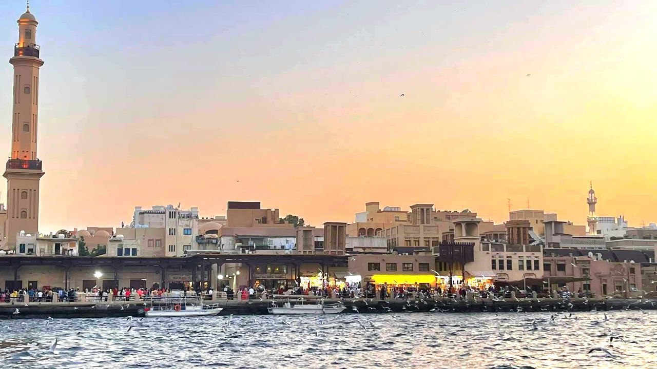 „Der Dubai Creek am Abend bei Sonnenuntergang mit einer stimmungsvollen Aussicht auf die historische Umgebung.“