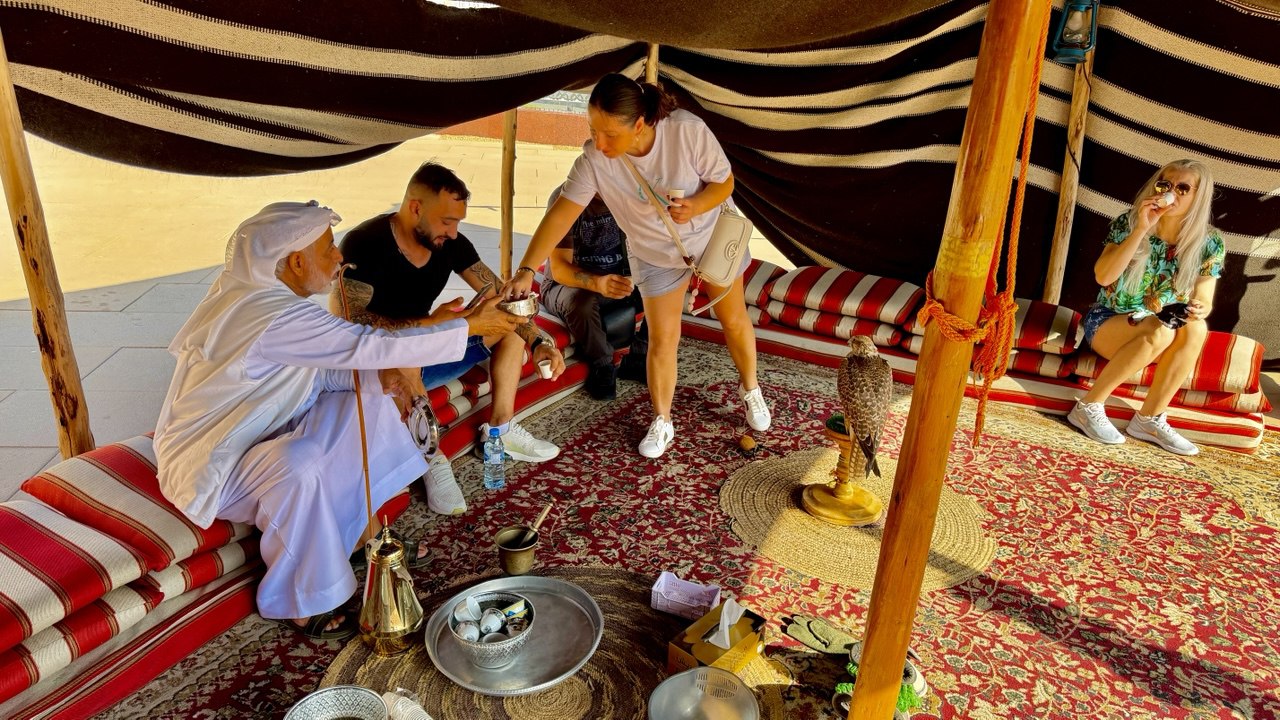 „In einem traditionellen Zelt genießen Gäste arabischen Kaffee (Gahwa) und Datteln als Zeichen der emiratischen Gastfreundschaft.“